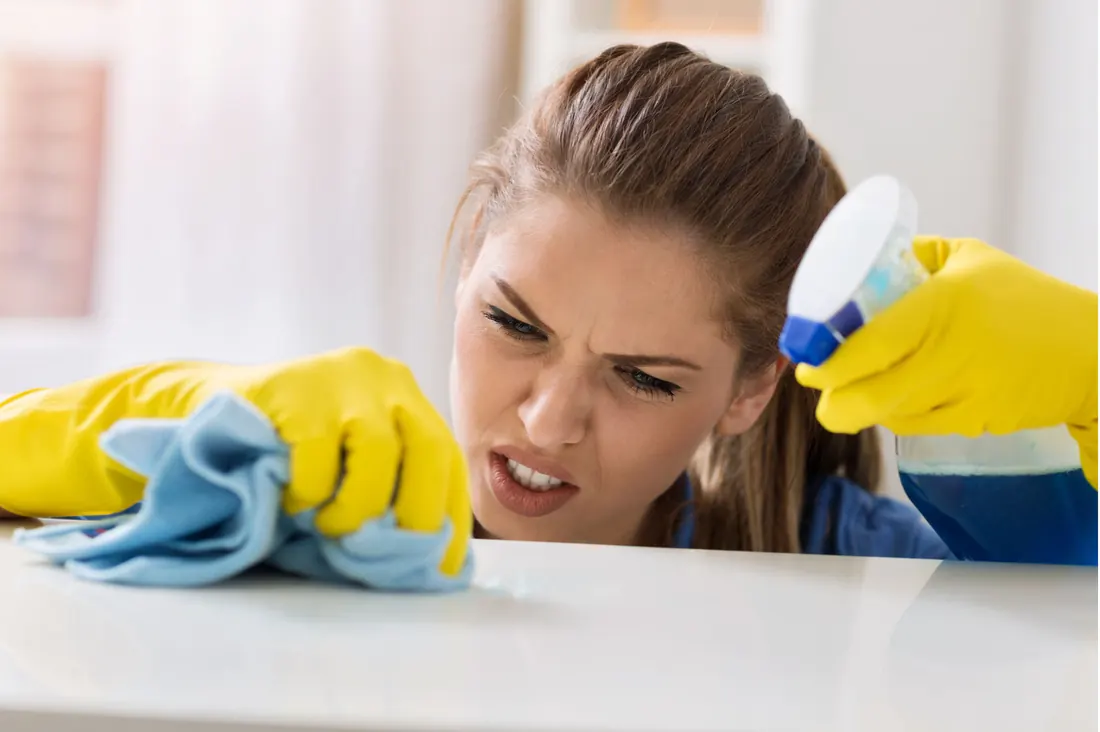 Cleaner wiping down a work surface with a microfiber cloth
